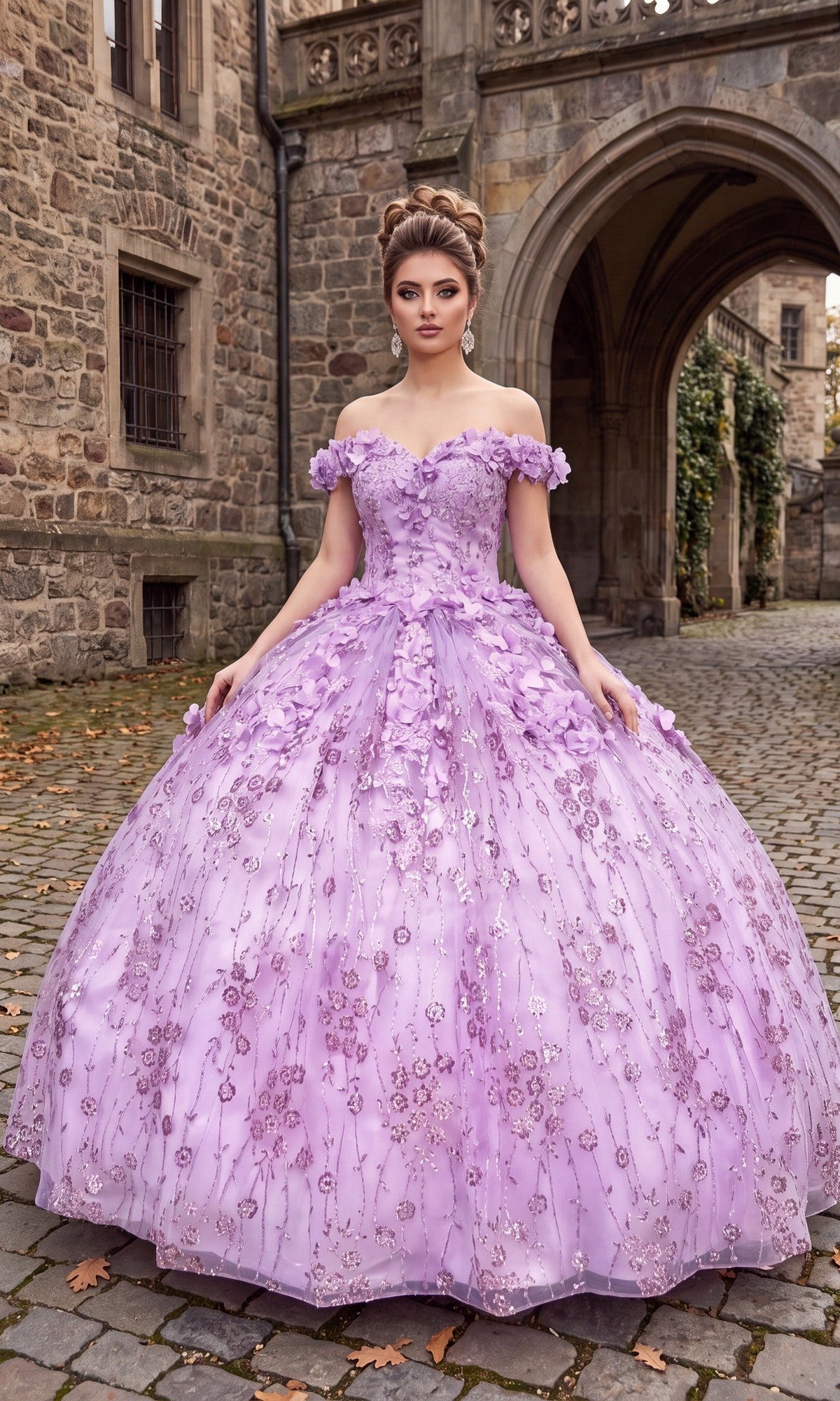 A woman stands on a cobblestone path in front of a stone building, wearing the Quinceanera Dress CHF3020 by Chicas in lilac, featuring a voluminous silhouette with elegant off-the-shoulder sleeves and intricate 3D flower applique.